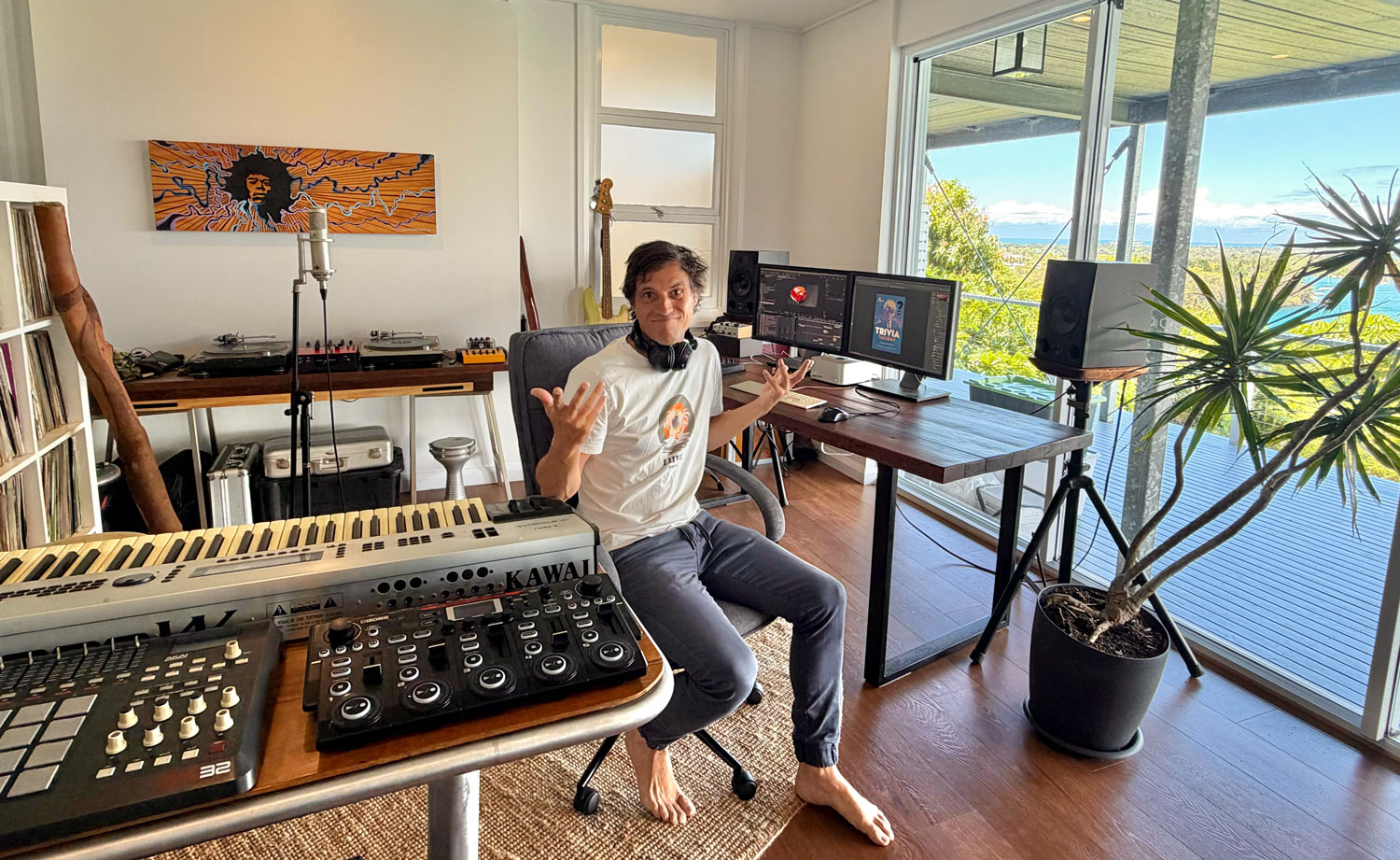 Freddy in his Northern NSW home studio, surrounded by keyboards, turntables and screens, with the coast beyond the window.